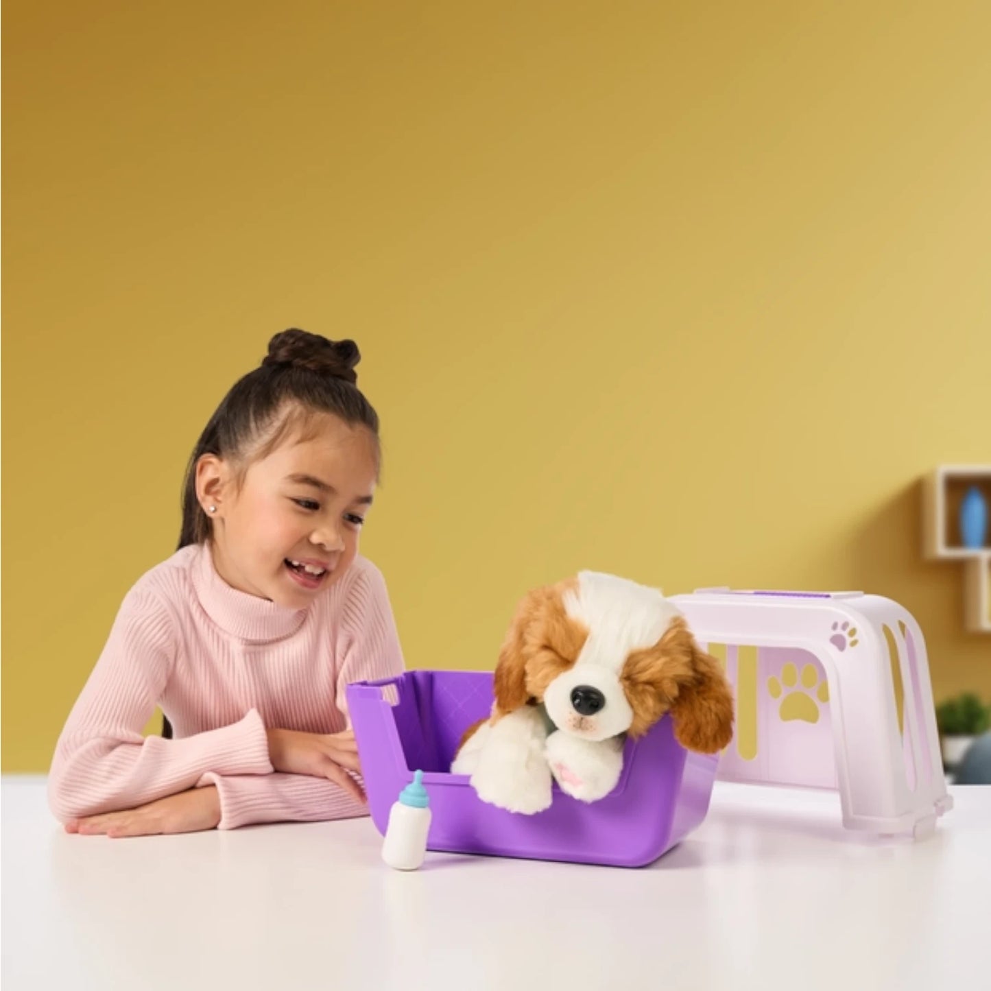 Child playing with a Little Live Pets - My Really Real Puppy Patches plush toy dog in a purple pet carrier against a yellow wall.