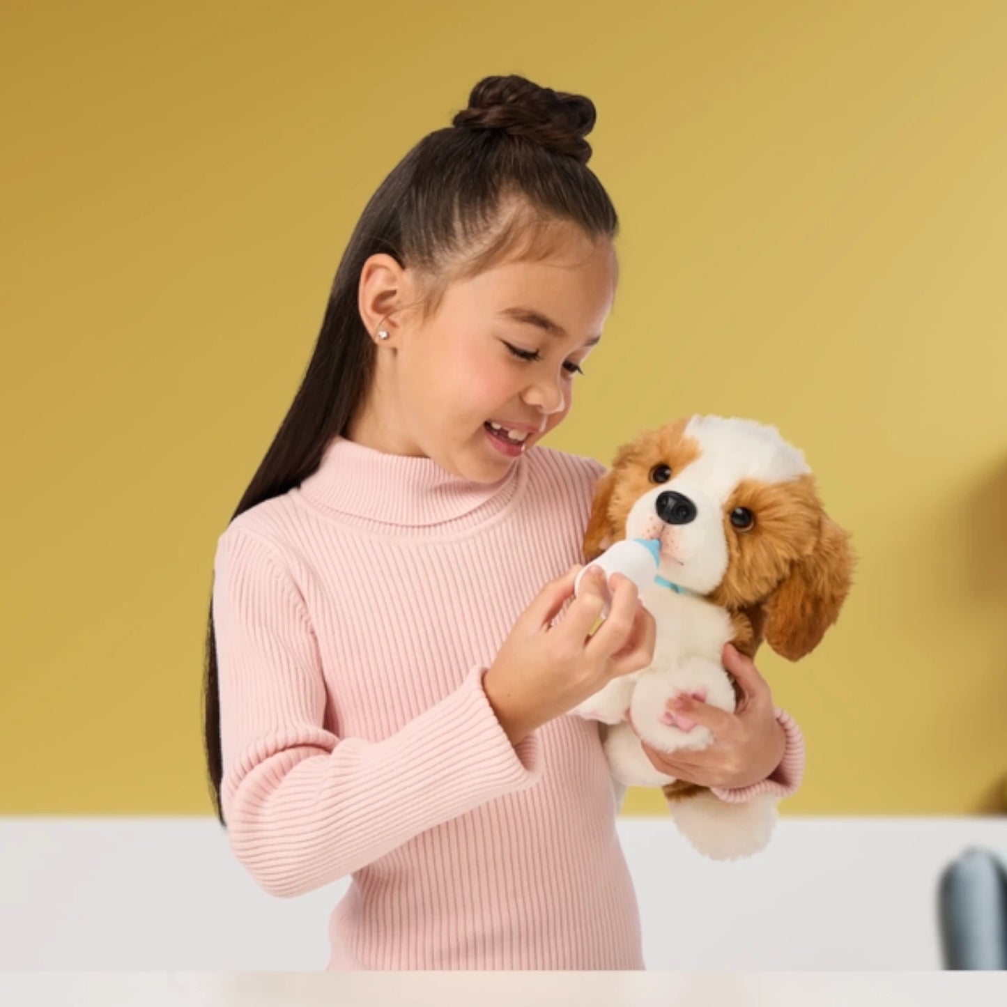 Young girl holding a Little Live Pets - My Really Real Puppy Patches plush toy dog against a yellow background