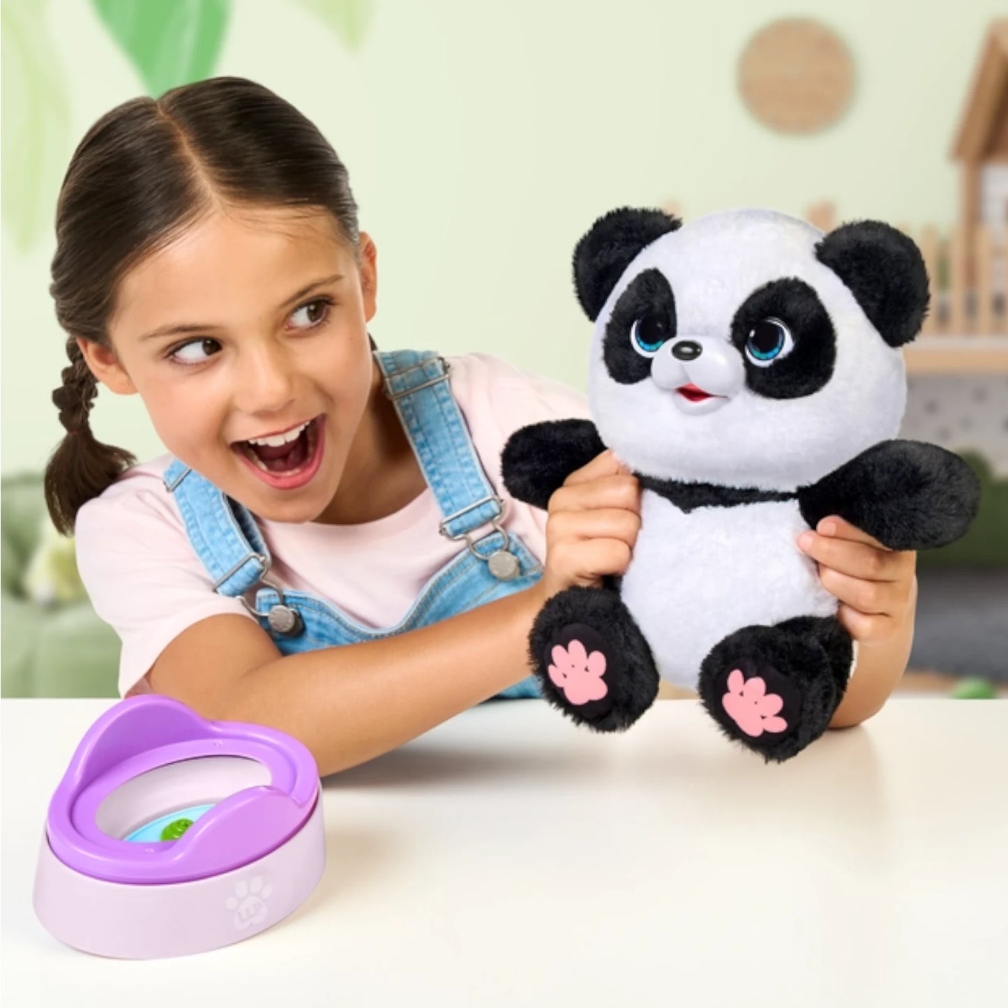 Child holding a Little Live Pets - My Baby Panda Chuchu plush panda toy with a purple electronic device on a light surface.
