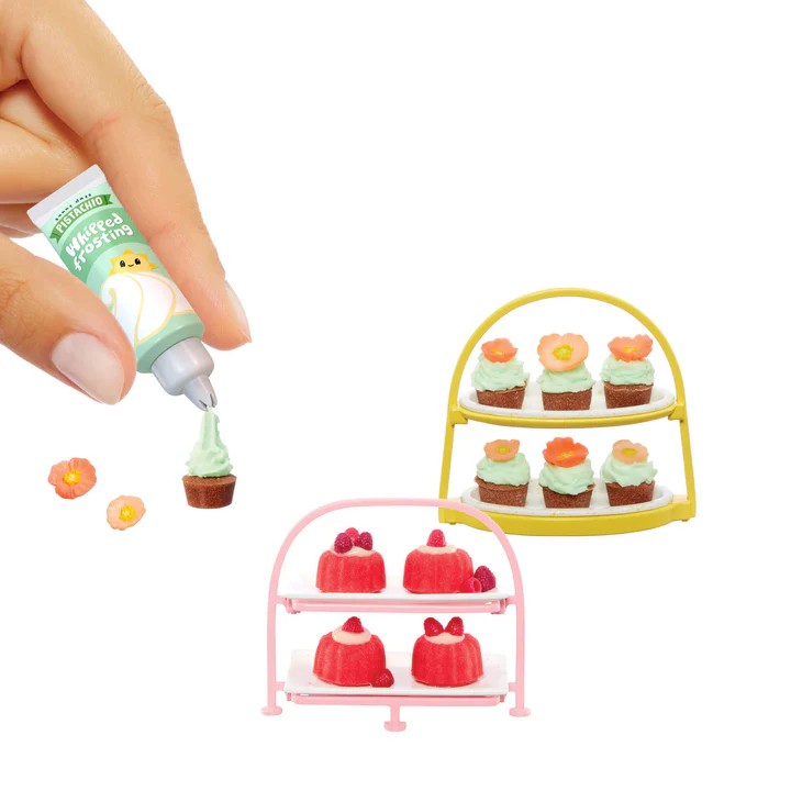 Miniature cakes on stands with a hand applying green icing. Miniverse Make It Mini From Scratch Series 2