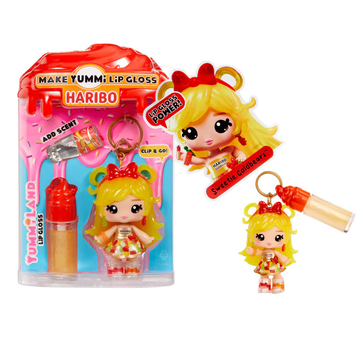 Yummiland x Haribo Goldbears lip gloss doll with yellow hair, a dress featuring gummy bear print, and red boots, shown with DIY lip gloss kit components including gold lip gloss tube, scented liquid packet, stirring spoon, and keychain ring.