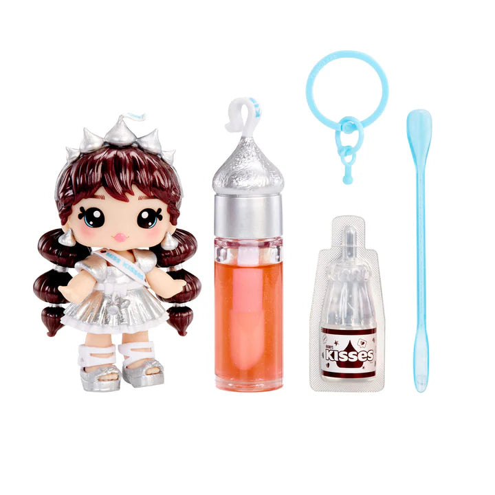 Yummiland x HERSHEY'S KISSES lip gloss doll with brown hair, wearing a silver dress and crown, shown with DIY lip gloss kit components including silver-topped lip gloss tube, scented liquid packet, stirring spoon, and keychain ring.