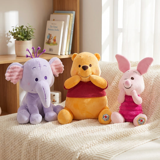 Three plush toys (Winnie the Pooh, Heffalump and Piglet) sitting on a couch with a bookshelf in the background.