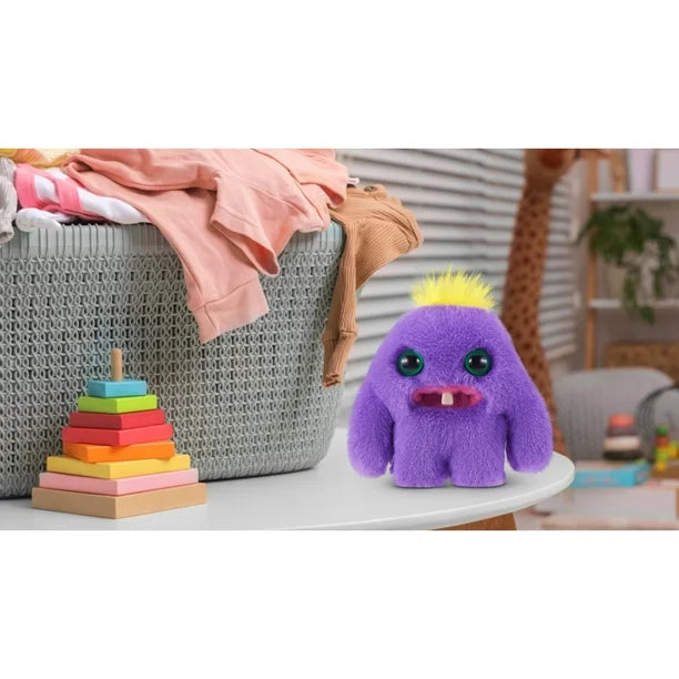 Purple plush toy with yellow hair on a table next to colorful blocks