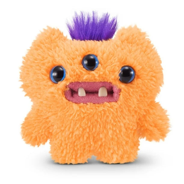A small, shaggy orange Fuggler Baby Fugg plush toy (Reek-O) with three blue eyes across its face, three white baby teeth showing in a pink mouth, and a spiky purple tuft of hair on top.