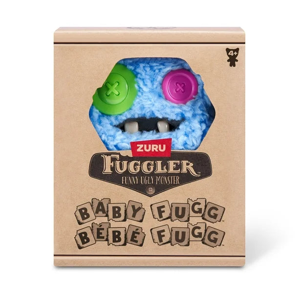 Display box of A small, shaggy blue Fuggler Baby Fugg plush toy (SaBQuoosh) with mismatched button eyes (one green, one pink), two white baby teeth showing, and a spiky pink tuft of hair on top.