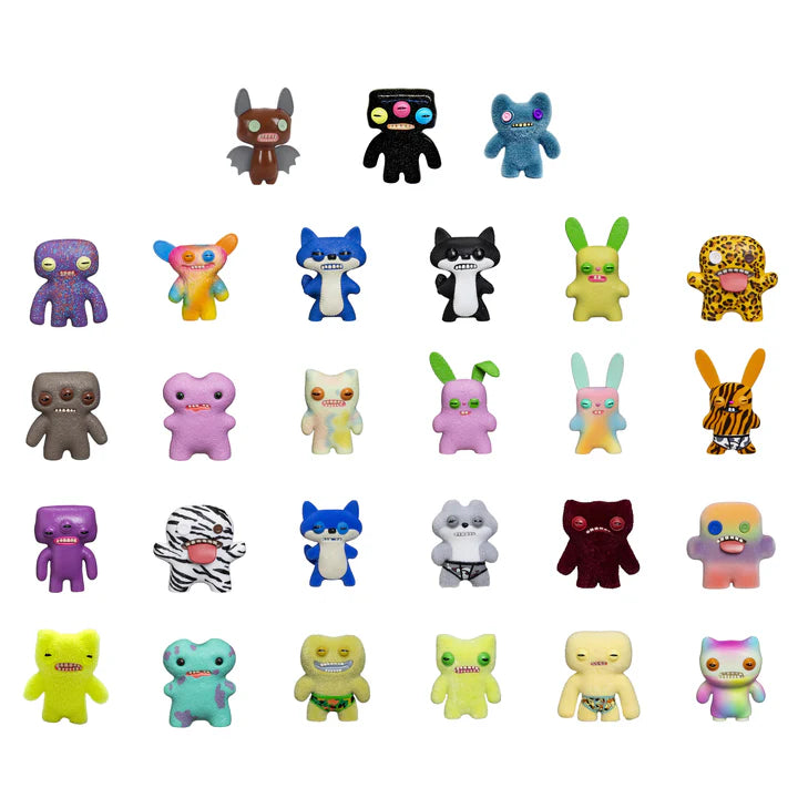 An array of 24 different colourful Fuggler mini collectible figures with various designs, expressions, and signature teeth showing.