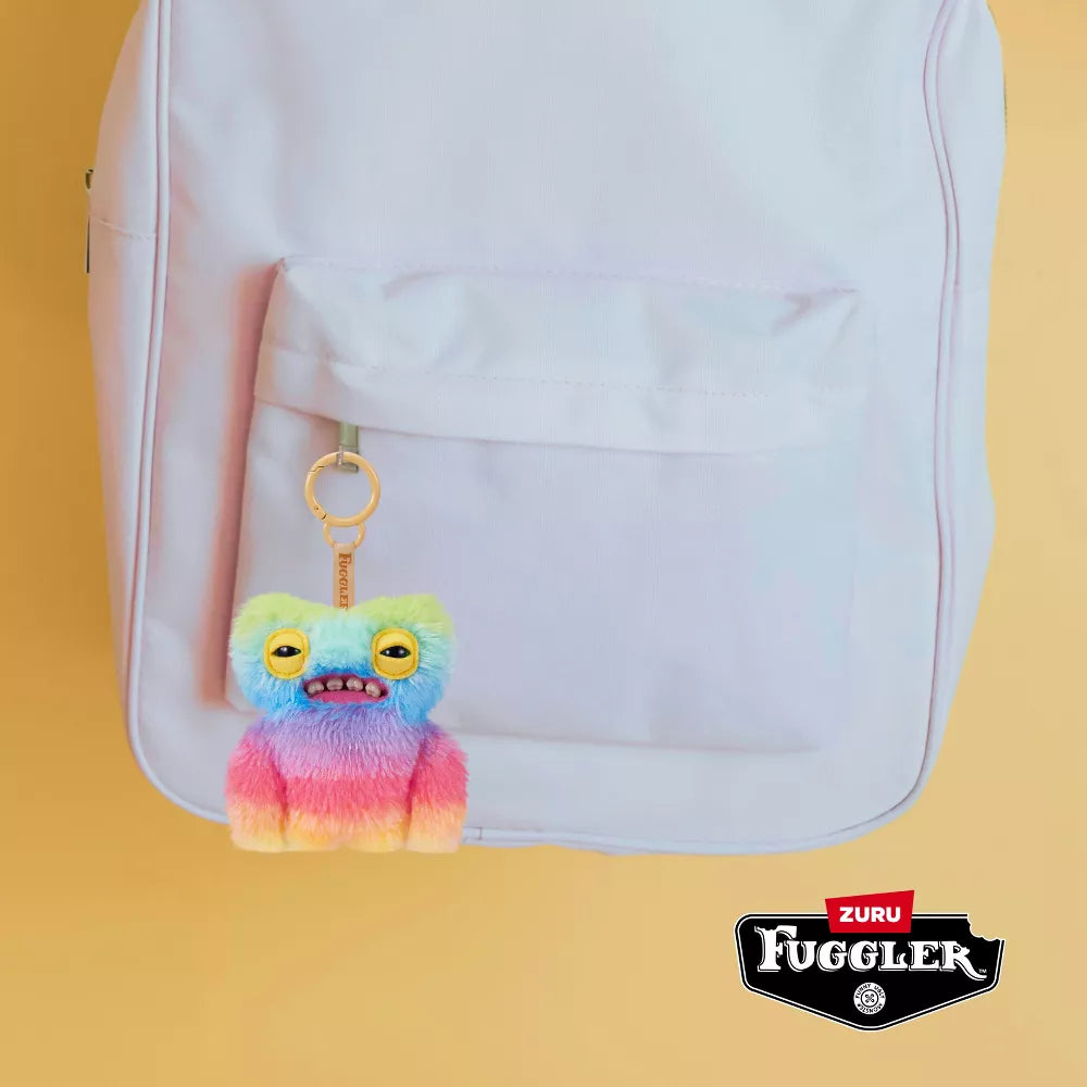 Colorful Fuggler keychain attached to a white backpack on a yellow background
