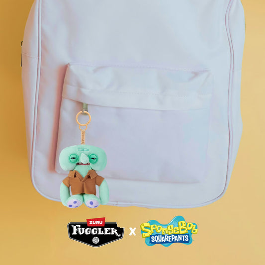 Plush keychain with character design on a backpack against a yellow background, featuring Zuru Fuggler and SpongeBob SquarePants logos.