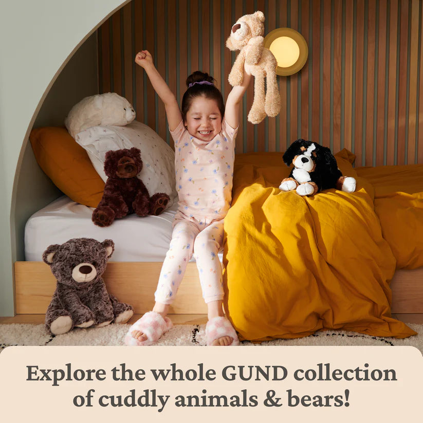 Child playing with stuffed animals in a bedroom, with text promoting the GUND collection.