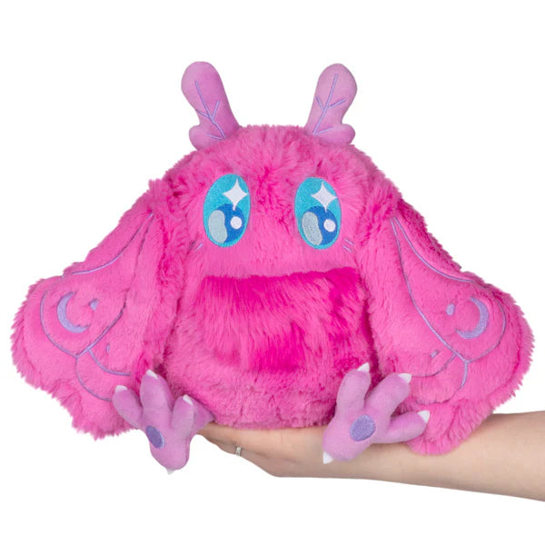 Squishable Mini Pink Baby Mothman plush toy with blue accents held in a hand on a white background