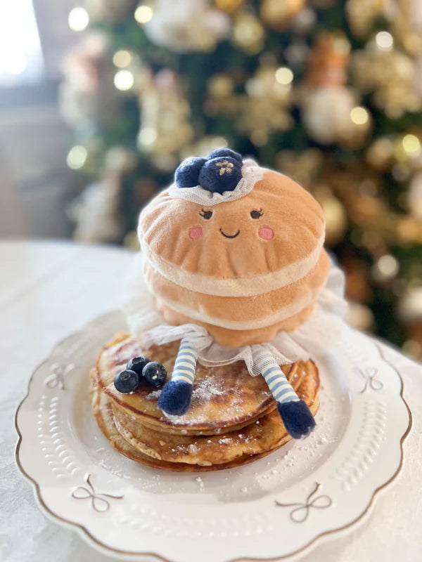 Mon Ami Pretty Pancake plush with golden layers, tulle trim, blueberry crown with blueberries on a plate in front of a decorated Christmas tree.