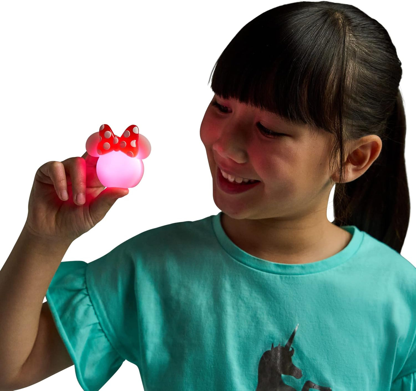Child holding a glowing red and pink object with a bow on a white background