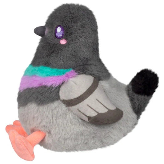 Squishable Snacker Pigeon S1E4 plush resting in hands, featuring soft grey fur, a bright purple and teal neck band, and little orange feet.