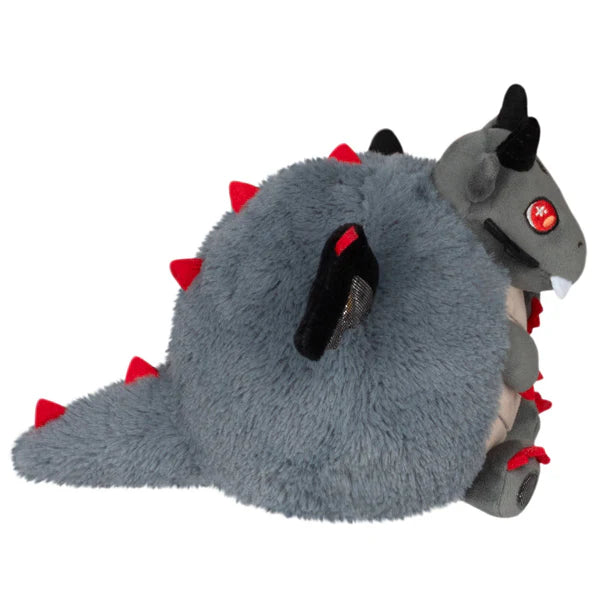 Plush toy resembling a dragon with red spikes on a white background