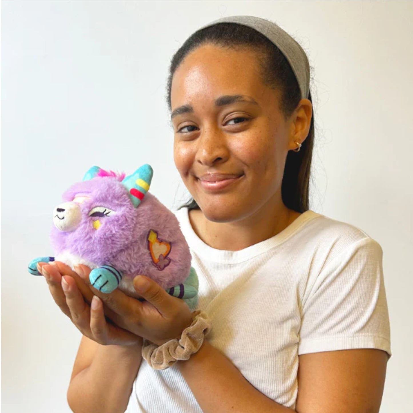 person holding squishable Decora Kitsune plush with colorful bows and accessories