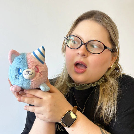 Person holding a plush toy with a surprised expression on a plain background