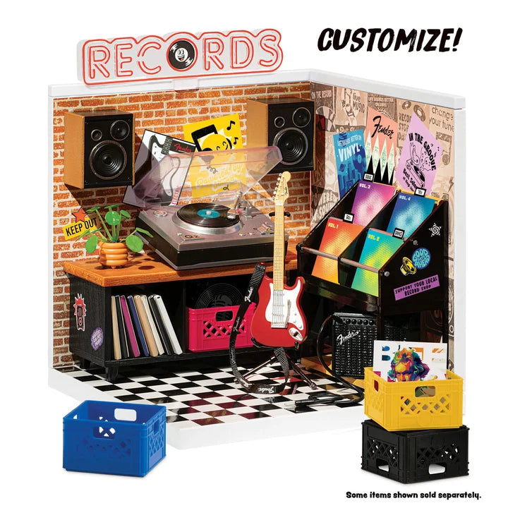 Toy record player setup with speakers, records, and a guitar on a checkered floor.