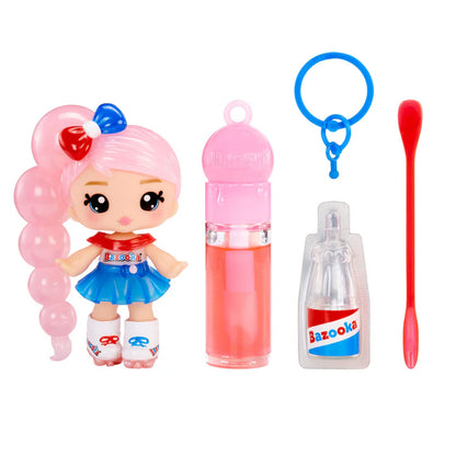 Yummiland x Bazooka Bubble Gum lip gloss doll with pink hair styled like bubbles, wearing a red, white, and blue outfit, shown with DIY lip gloss kit components including pink lip gloss tube, scented liquid packet, stirring spoon, and keychain ring.