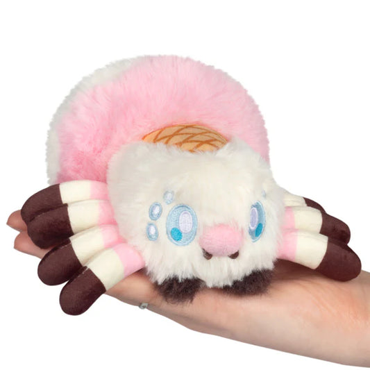 Squishable Alter Egos Series 20 Ice Cream Spider plush held in a hand, featuring fluffy white and pink fur, a waffle cone detail, and brown striped legs.