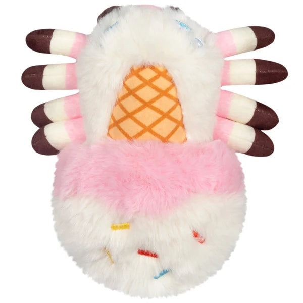 Squishable Alter Egos Series 20 Ice Cream Spider plush held in a hand, featuring fluffy white and pink fur, a waffle cone detail, and brown striped legs.