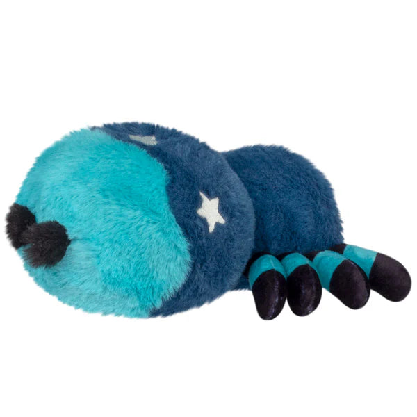 Squishable Alter Egos Series 20 Midnight Spider plush held in a hand, featuring deep blue fur, light blue striped legs, green eyes, and white moon and star details.