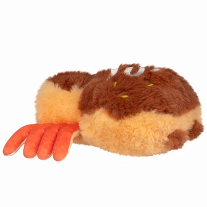 Squishable Alter Egos Series 20 Takoyaki Spider plush held in a hand, featuring golden-brown fur with white drizzle embroidery, orange tentacle legs, and green eyes.