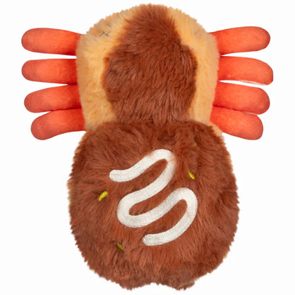 Squishable Alter Egos Series 20 Takoyaki Spider plush held in a hand, featuring golden-brown fur with white drizzle embroidery, orange tentacle legs, and green eyes.