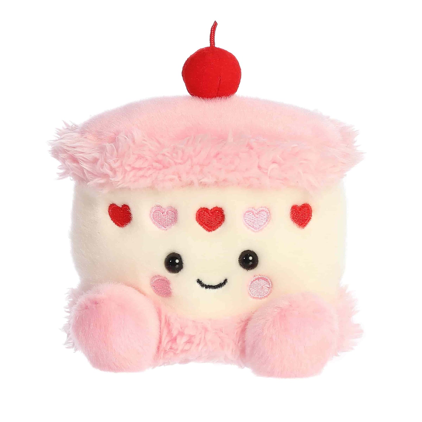 Product view of Aurora Palm Pals Jubi Heart Cake, a small plush cake with pink frosting, heart sprinkles, and a cherry on top.