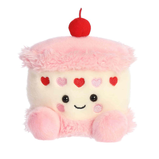 Product view of Aurora Palm Pals Jubi Heart Cake, a small plush cake with pink frosting, heart sprinkles, and a cherry on top.