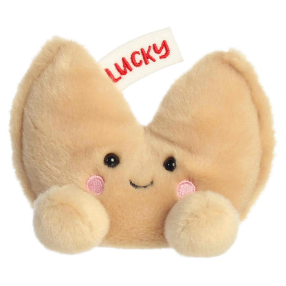Aurora Palm Pals Lucky Fortune Cookie plush food character featuring golden-brown fur, an embroidered fortune slip reading LUCKY, and rosy cheeks sitting upright.