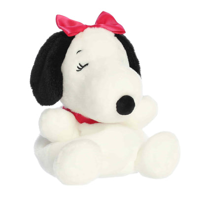 Product view of Aurora Palm Pals Peanuts Belle plush featuring a red bow, red collar, and a heart-shaped spot on her back.