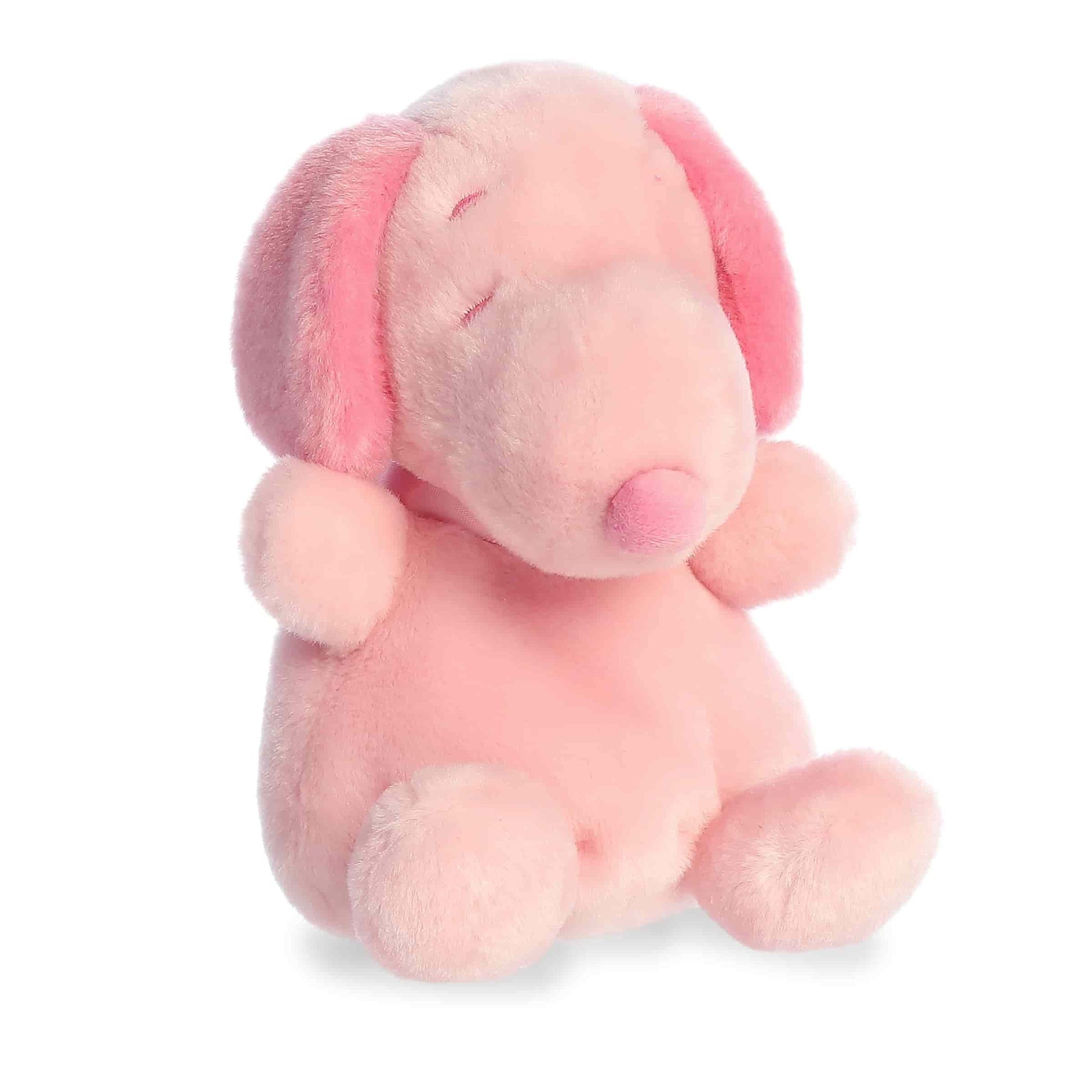 Product view of Aurora Palm Pals Peanuts Snoopy Pink, a small beagle plush with pink ears, nose, and spot, sitting in a relaxed pose.