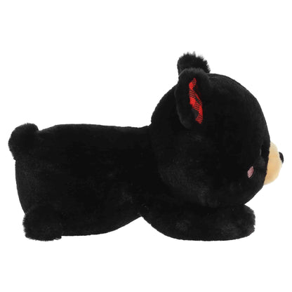 Aurora Too Cute Ben Black Bear plush lying belly-down featuring soft black fur, a tan snout, rosy cheeks, and red buffalo plaid inner ears.