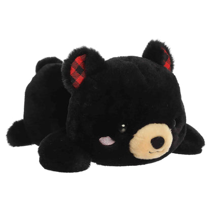 Aurora Too Cute Ben Black Bear plush lying belly-down featuring soft black fur, a tan snout, rosy cheeks, and red buffalo plaid inner ears.