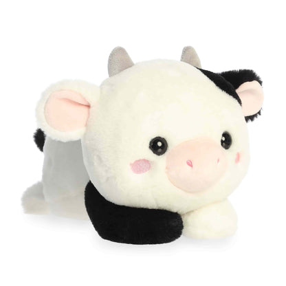 Aurora Too Cute Cayce Cow 9-inch plush soft toy, a black and white spotted cow with pink blushing cheeks and grey horns in a lay-flat pose.