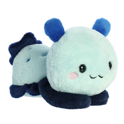 A product photo of the 9-inch Aurora Too Cute Seela Sea Slug plush, a light blue plush with dark blue fins, shown lying belly-down with its paws sprawled out on a white background.