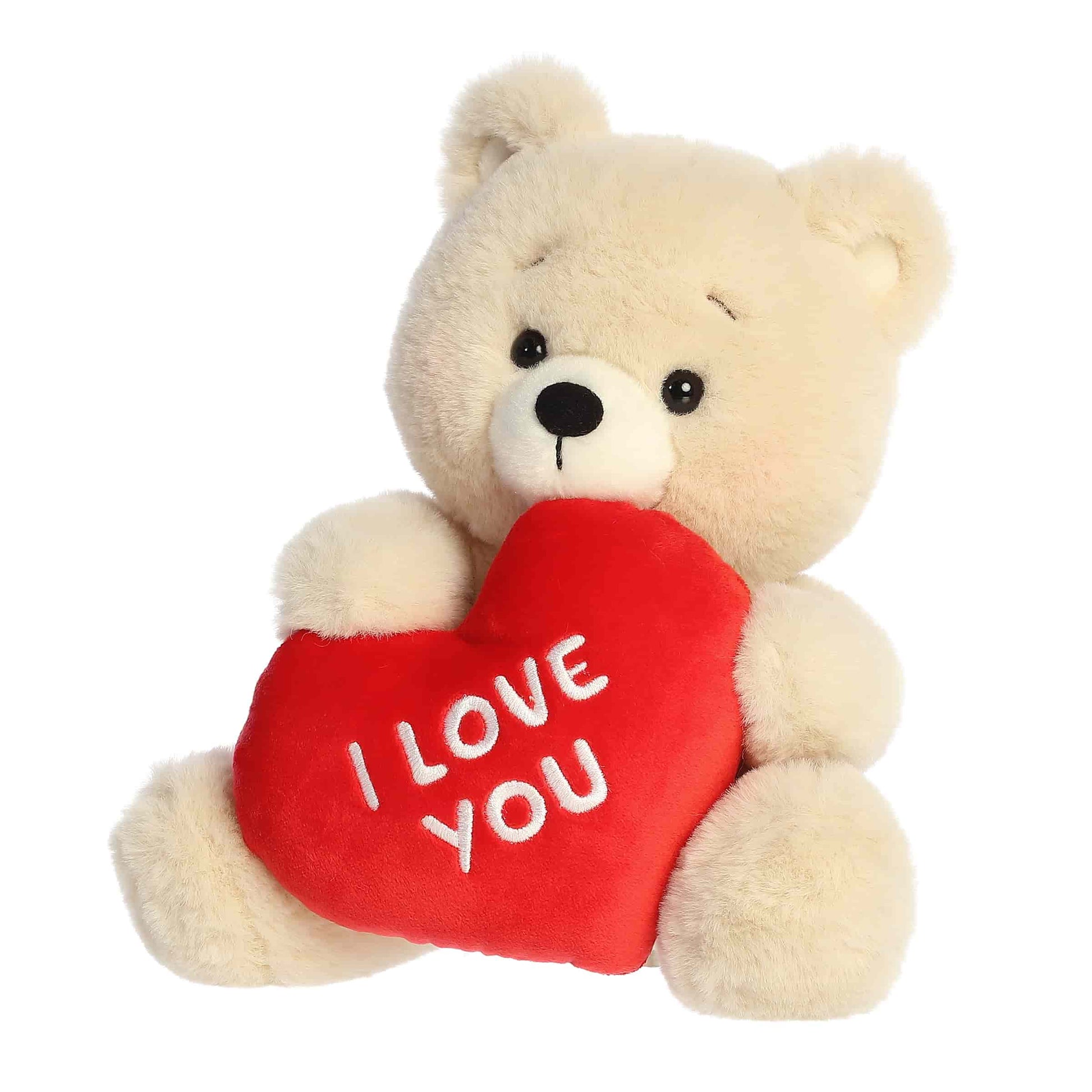 Angled  view of Aurora Valentine Beary Sweet Bear plush, a cream teddy bear holding a red heart that says I Love You.