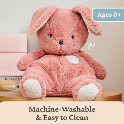 Pink plush toy with bunny ears on a wooden surface, with text indicating machine-washability.
