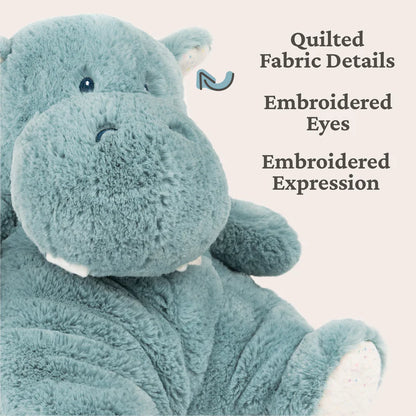 Teal plush hippo toy with quilted fabric details and embroidered expression on a light beige background.