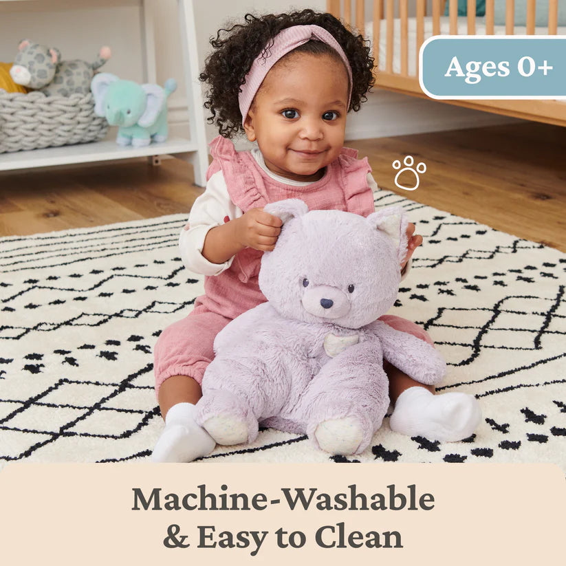 Baby holding a plush toy in a nursery setting with text about machine-washability.