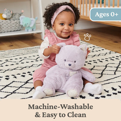 Baby holding a plush toy in a nursery setting with text about machine-washability.