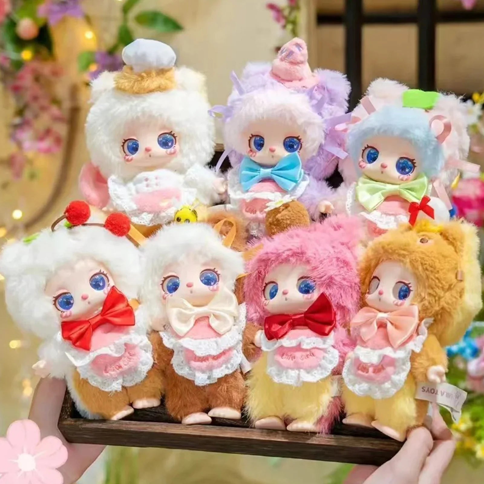 A group shot of the 7 adorable plush dolls from the Baby Three Liila V4 Pastry Chef Kitten collectible series, held in a wooden tray.