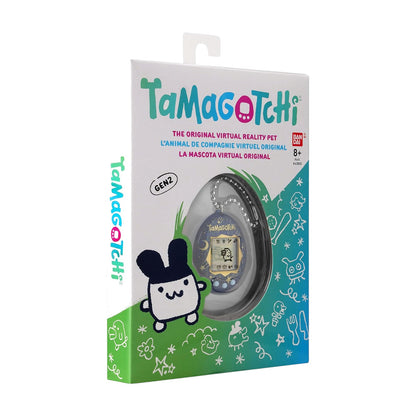 Tamagotchi retail packaging showing the original virtual reality pet inside a clear window, with colorful cartoon graphics and the Tamagotchi branding on a white, green, and blue box.
