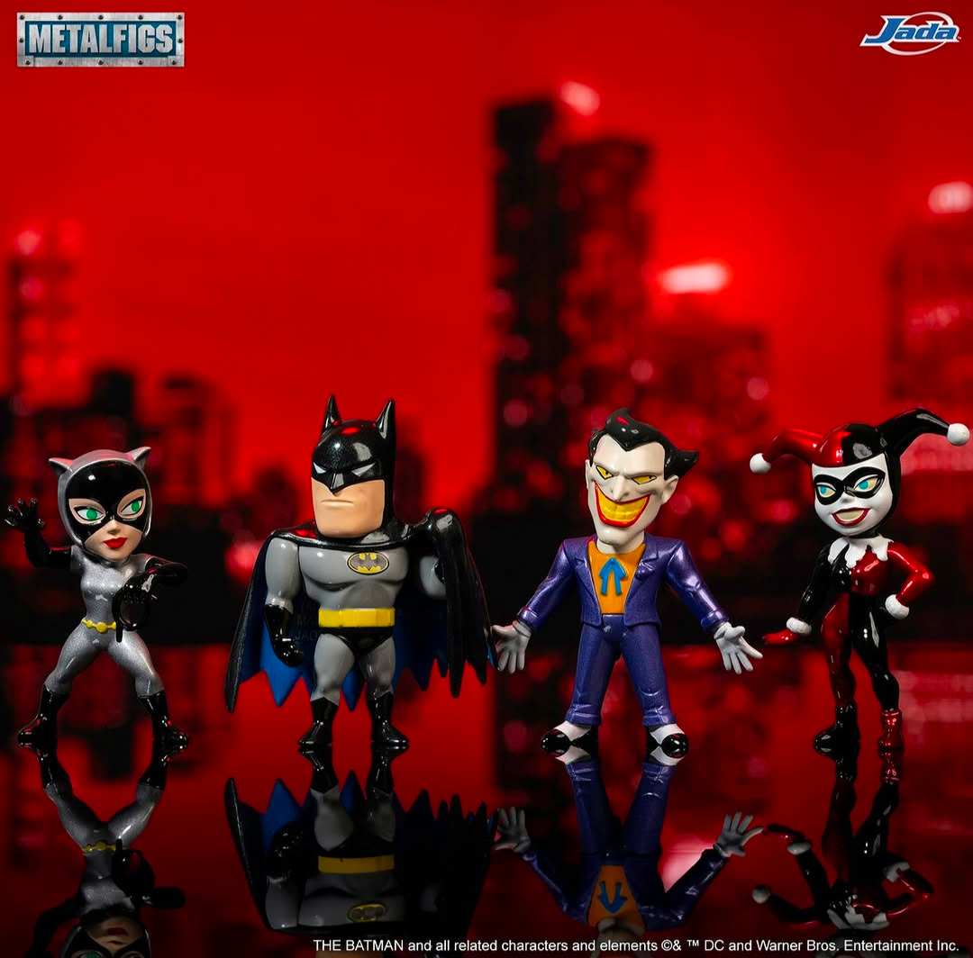 Four Metalfigs collectible action figures of Batman, Catwoman, the Joker, and Harley Quinn standing in a row against a red-lit blurred cityscape background. The Metalfigs logo is in the top-left corner, and the Juwa Bros.