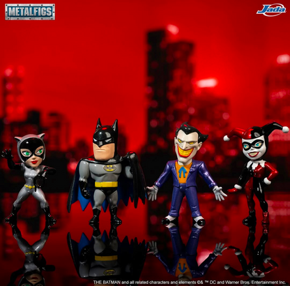 Four Metalfigs collectible action figures of Batman, Catwoman, the Joker, and Harley Quinn standing in a row against a red-lit blurred cityscape background. The Metalfigs logo is in the top-left corner, and the Juwa Bros.