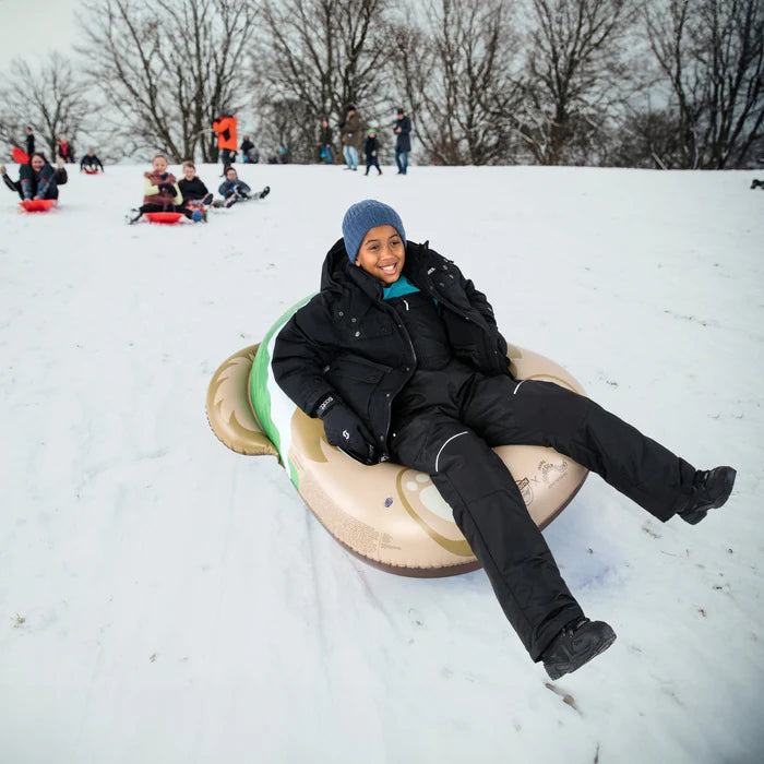 Person snow tubing in a snowy park with other people in the background