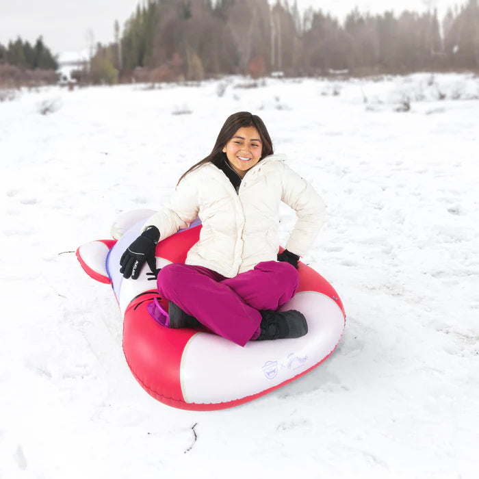 Person sitting on a red and white snow tube in a snowy field