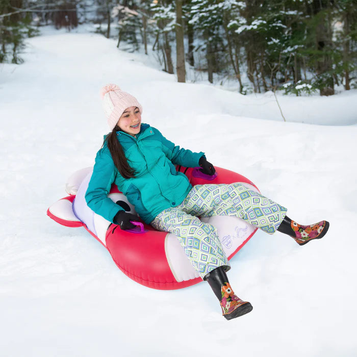 Person snow tubing down a snowy hill in a winter wonderland setting