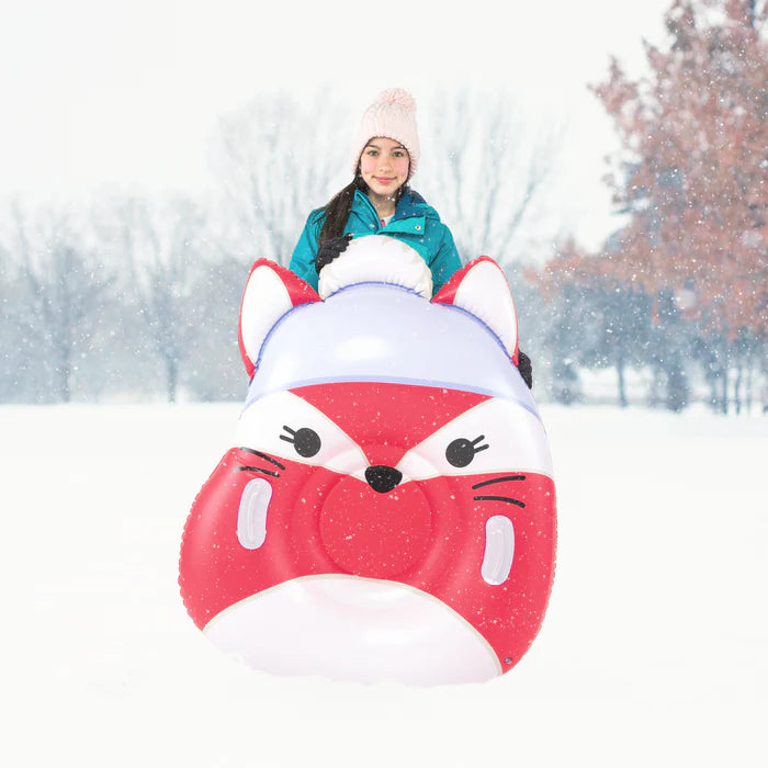 Person on a snow tube shaped like a fox in a snowy landscape